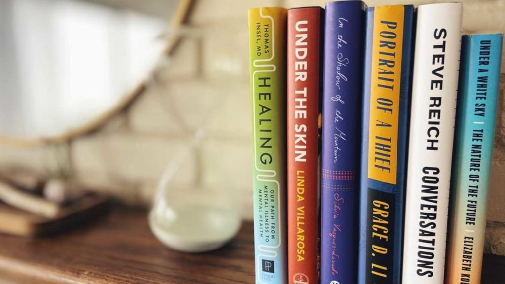 five recommend books on a table with a mirror and hourglass blurred in the background