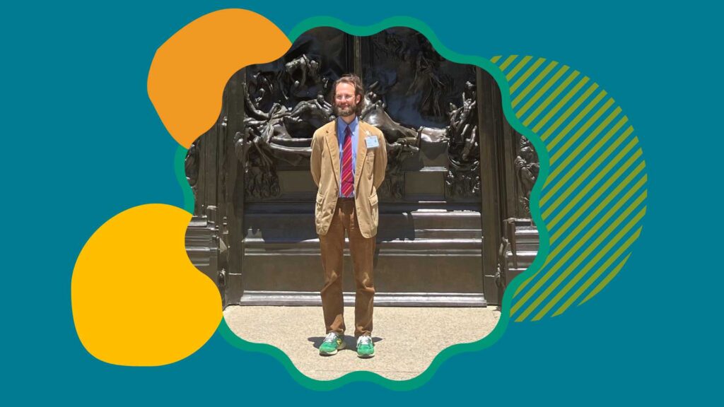 Riain is looking off from the camera in a tan blazer. He is standing in front of a Rodin sculpture on the Stanford University campus. Colorful shapes surround the photo on a teal background